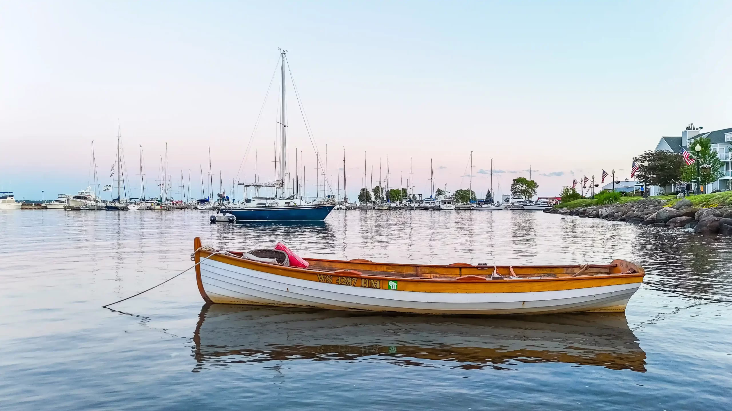A wooden rowboat moored in a still harbor at first light