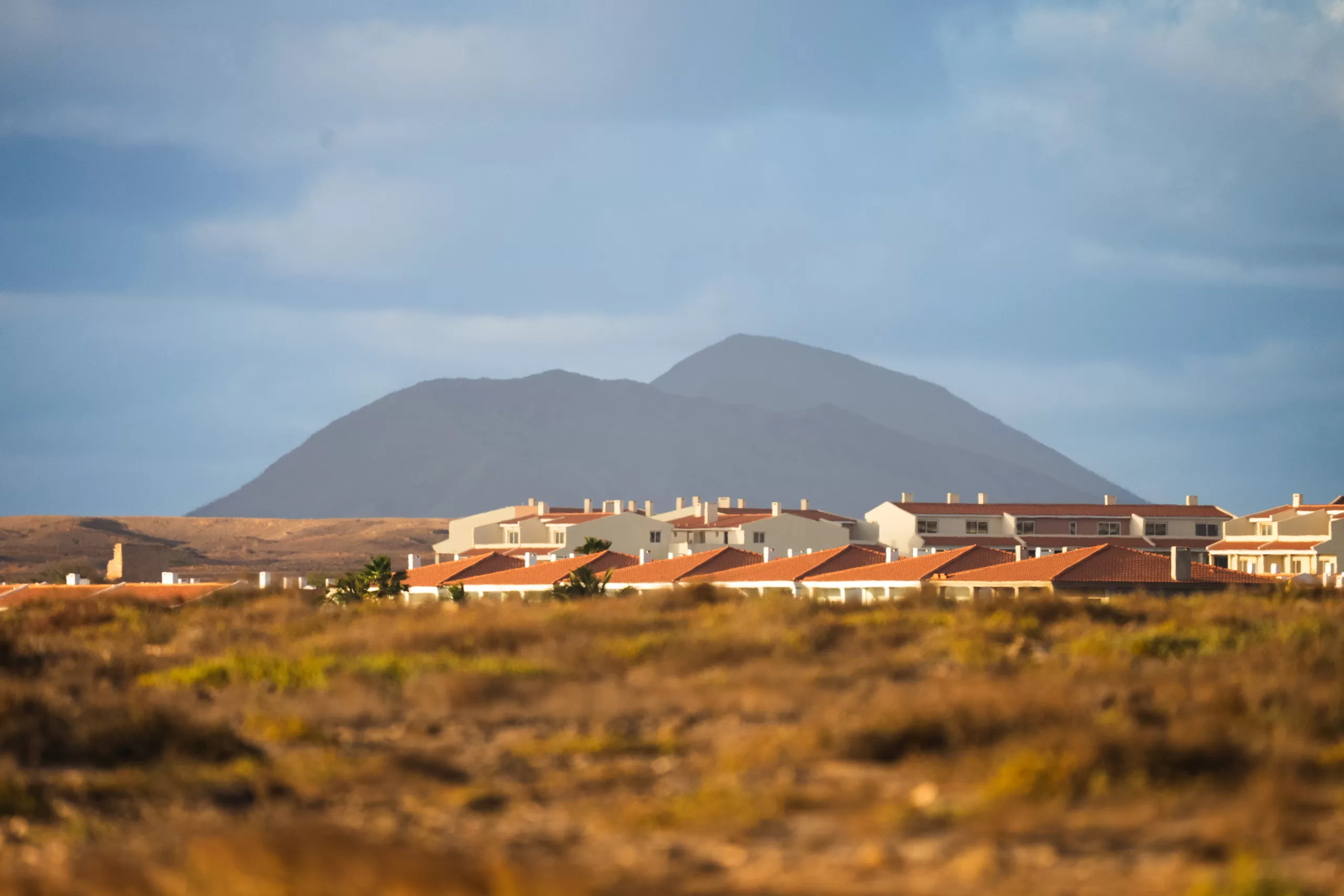 Low white houses below a volcanic peak